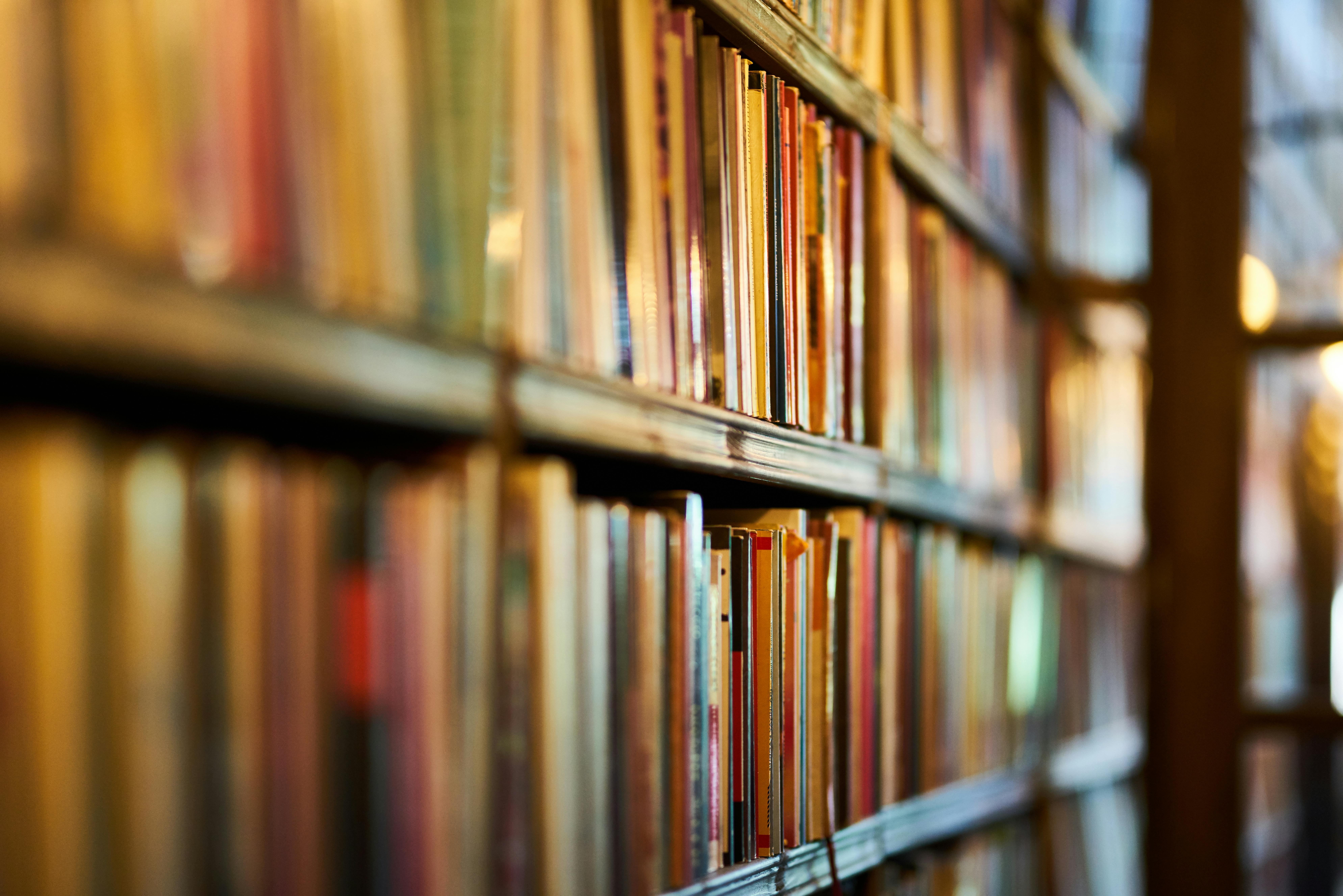 Selective focus photography of a brown wooden bookshelf