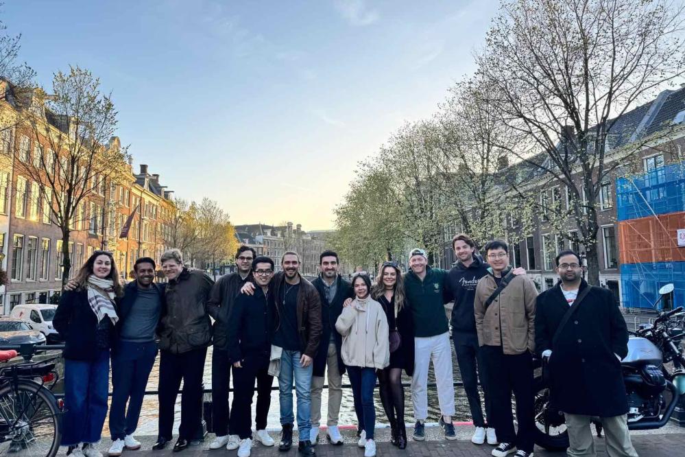 A photograph of a group of MSt in Real Estate students standing on a bridge in Amsterdam in wintery weather.
